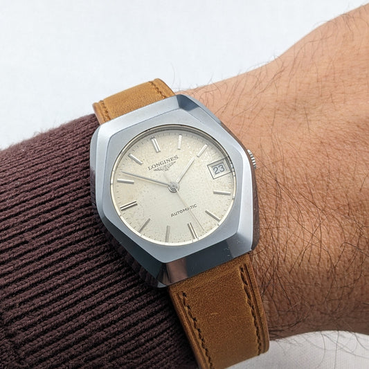 The LONGINES Automatic reference 3042-633 worn on a wrist, showing its cream dial, date window marked 23 and brown leather strap.