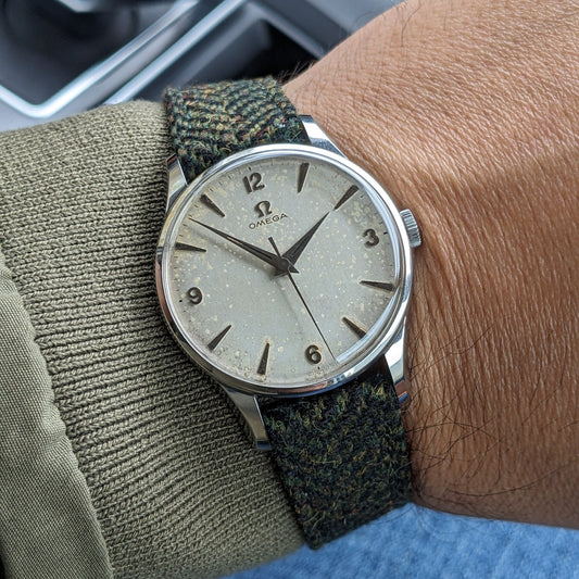Omega Classic reference 2810-2 SC worn on a wrist, showing its light numbered dial, polished case and green patterned strap.