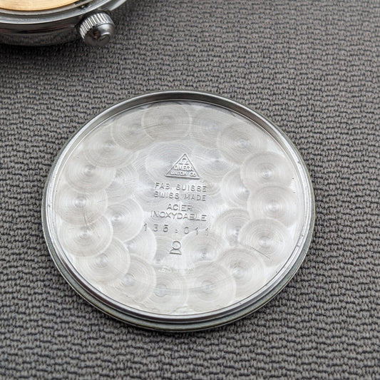 Omega Seamaster 600 reference 135.011 shown from the rear, with engraved caseback markings centered on gray fabric.