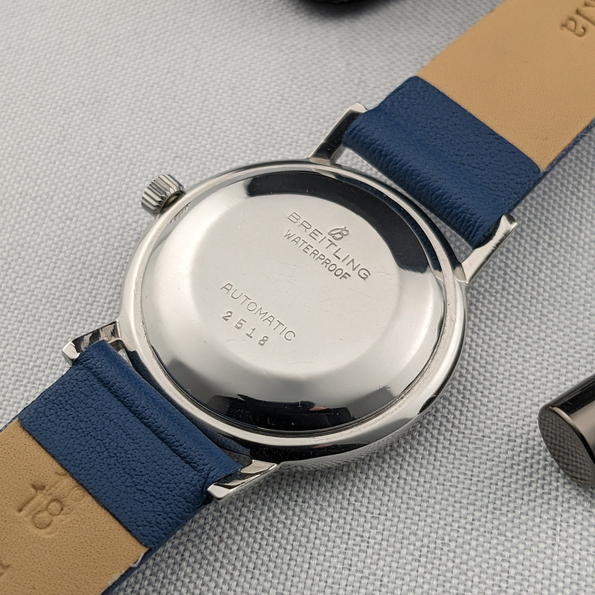 Breitling Automatic watch shown from the polished caseback, with visible Breitling, waterproof and automatic markings on a blue leather strap.