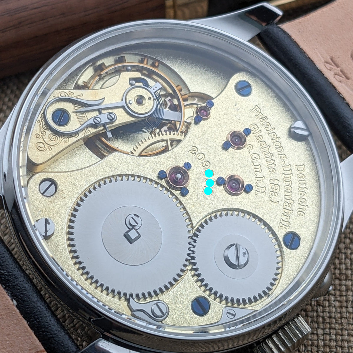 Deutsche Präzisionsuhr „Original Glashütte” von hinten durch ein transparentes Gehäuse, mit goldfarbenen Platinen,