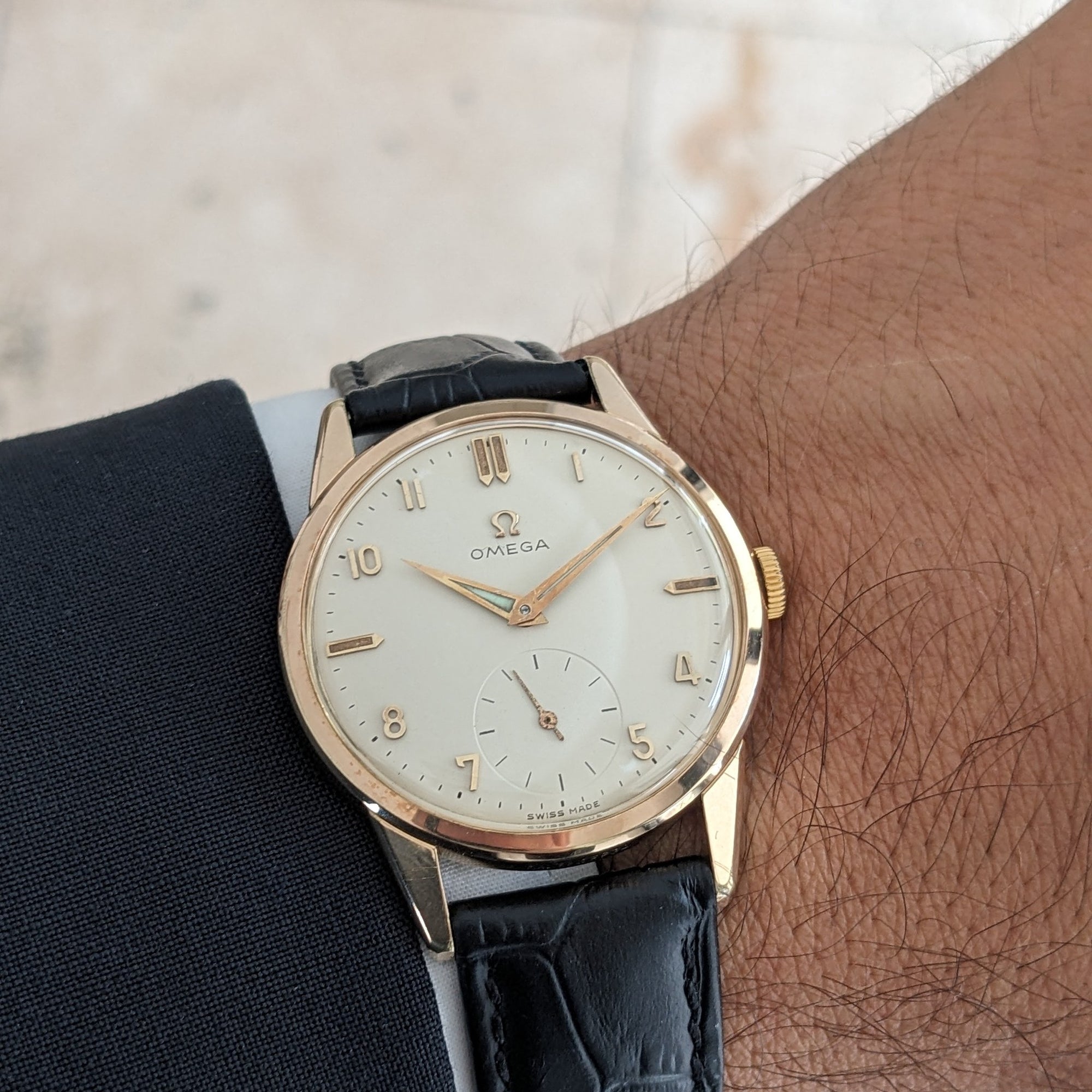Omega Classic reference 14391-1 on a wrist, showing its gold-tone round case, light dial, small seconds and black leather strap.