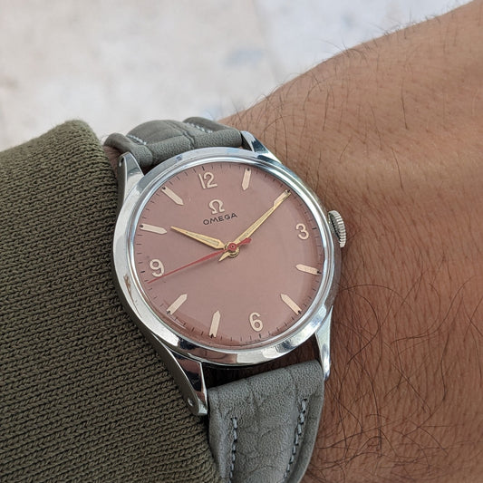 Omega Classic referenza 2760-6 SC in primo piano su un polso, con quadrante rosa, numeri applicati, lancette dorate e cinturino grigio.