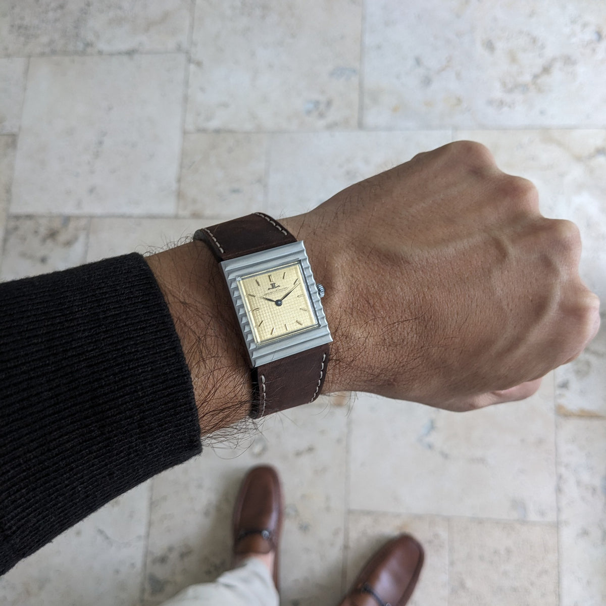 Jaeger-LeCoultre Vogue Tank Ref. 9120 am Handgelenk, mit rechteckigem goldfarbenem Zifferblatt, silberfarbenem Gehäuse und braunem Lederarmband.