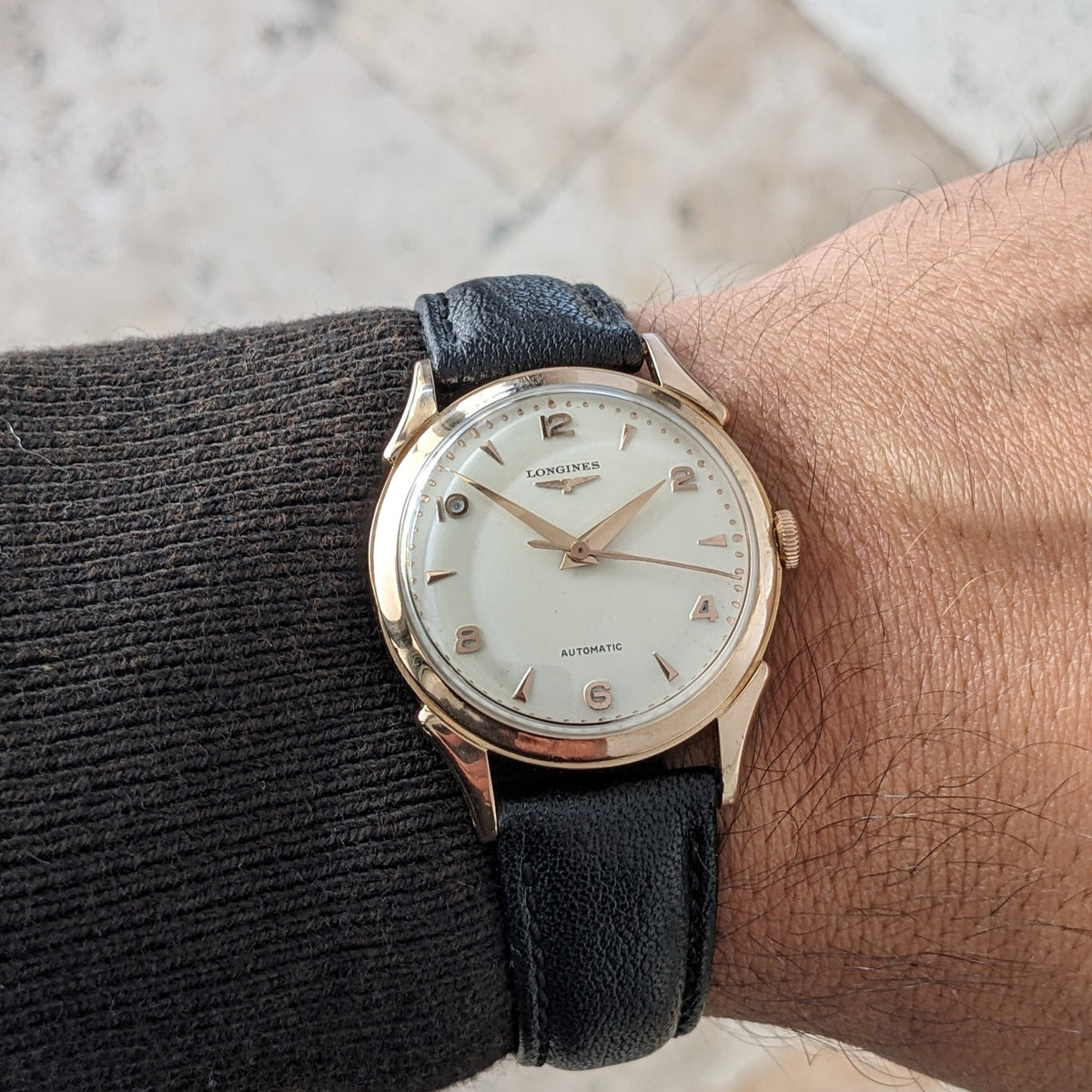 Longines Automatik Referenz 6058 am Handgelenk, mit hellem Zifferblatt, goldfarbenem Gehäuse, schwarzem Lederarmband und zentralen Zeigern.