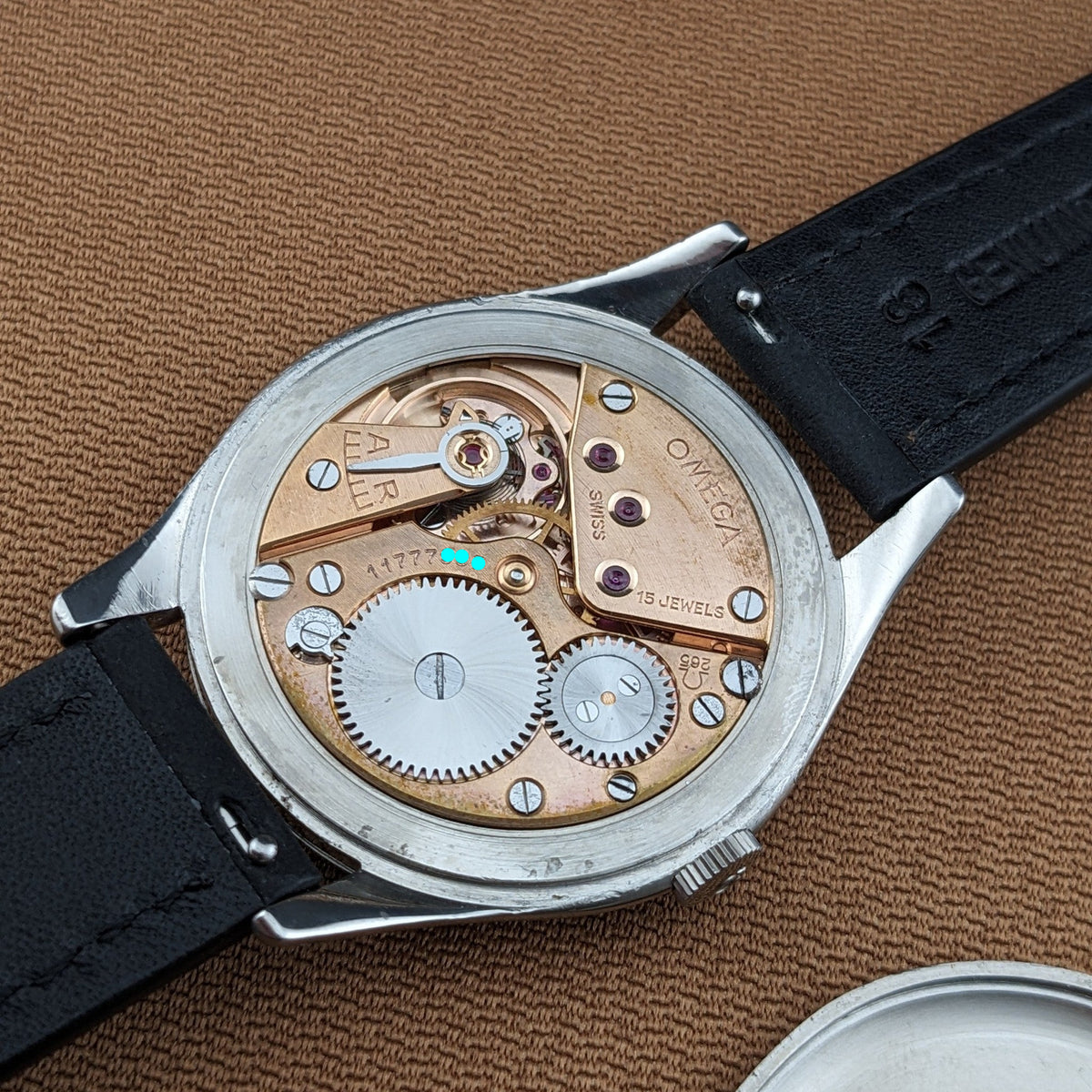 Omega Jumbo reference 2505-5 with its mechanical movement visible, including Omega markings, jewels, screws, gears, and black leather strap.