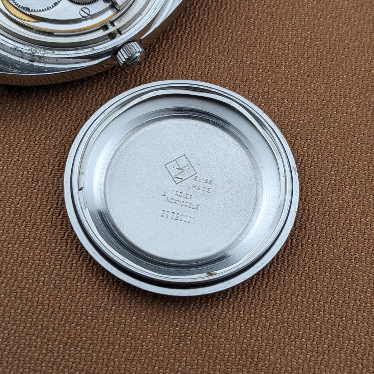 Zenith Automatic reference GR 720001 caseback shown separately, with stamped interior markings visible against brown fabric.