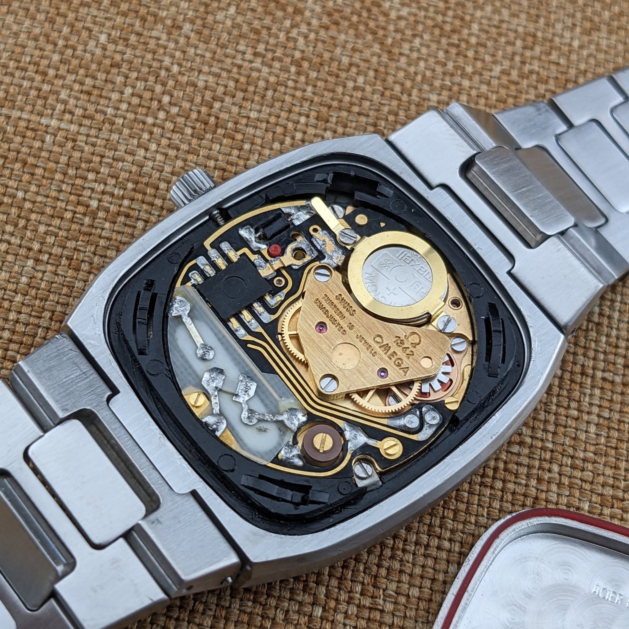 Open Omega Seamaster reference 196.0166 case displaying the gold-toned movement, battery, gears, bracelet, and detached caseback edge.