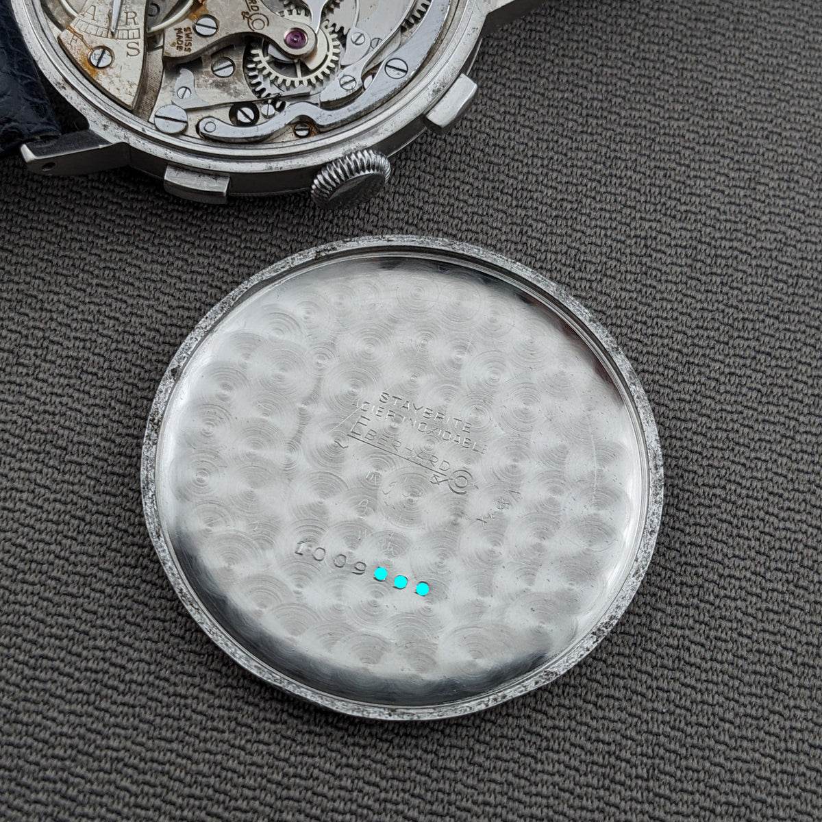 Detached inner caseback of the Eberhard & Co. Pre-Extra Fort lies below the visible movement, showing engraved markings and circular decoration.