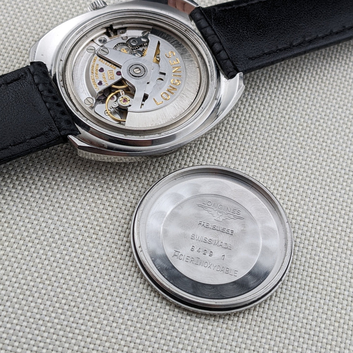 Longines Ultrachron reference 8429 displays the exposed movement above its detached caseback, with engraved markings visible inside the cover.