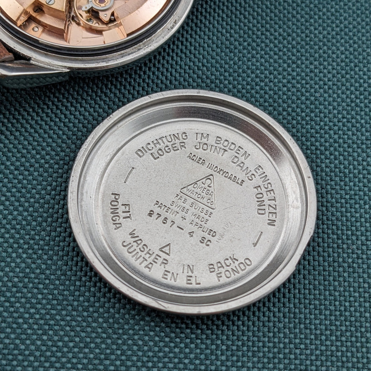 Detached caseback of the Omega Automatic Bumper reference 2767-4 SC shown interior-up, with engraved text and a central Omega medallion.