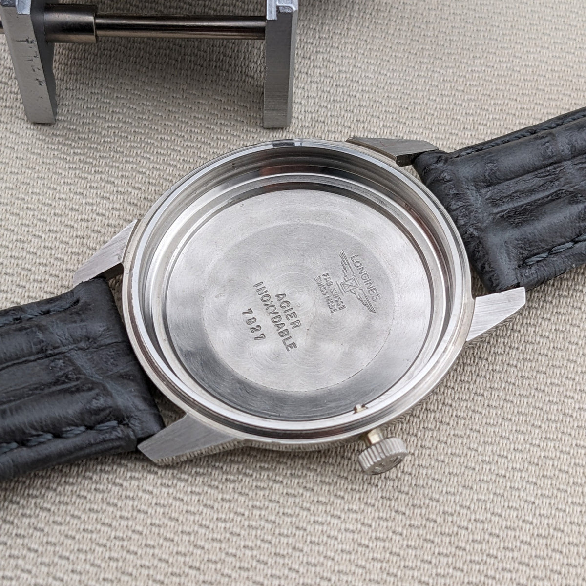 Longines Ultra-Chron 7827 inner caseback shown beside the movement holder, with engraved Longines and reference markings visible.