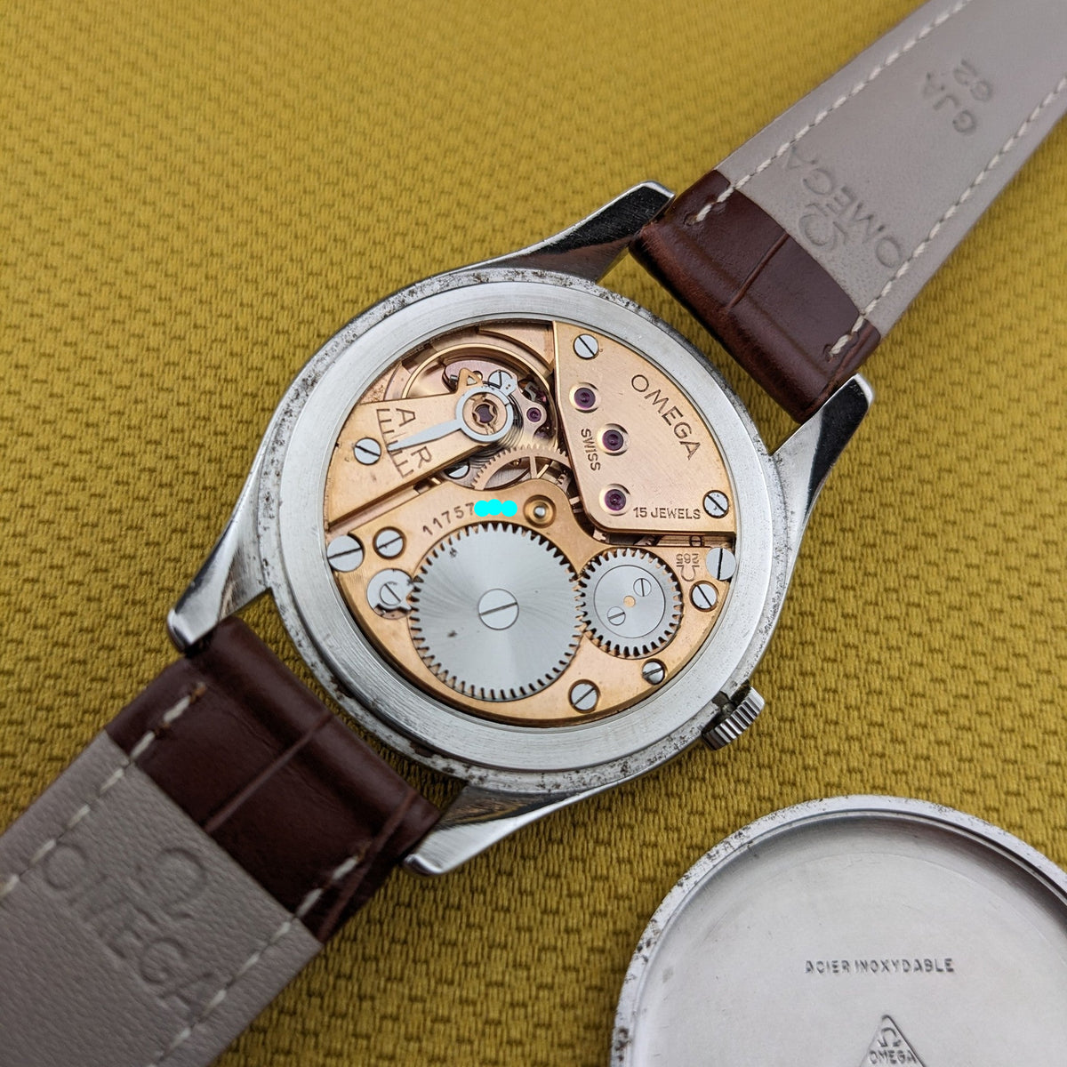 Omega Jumbo Referenz 2505-10 geöffnet mit sichtbarem mechanischem Werk neben dem abgenommenen runden Gehäuseboden.