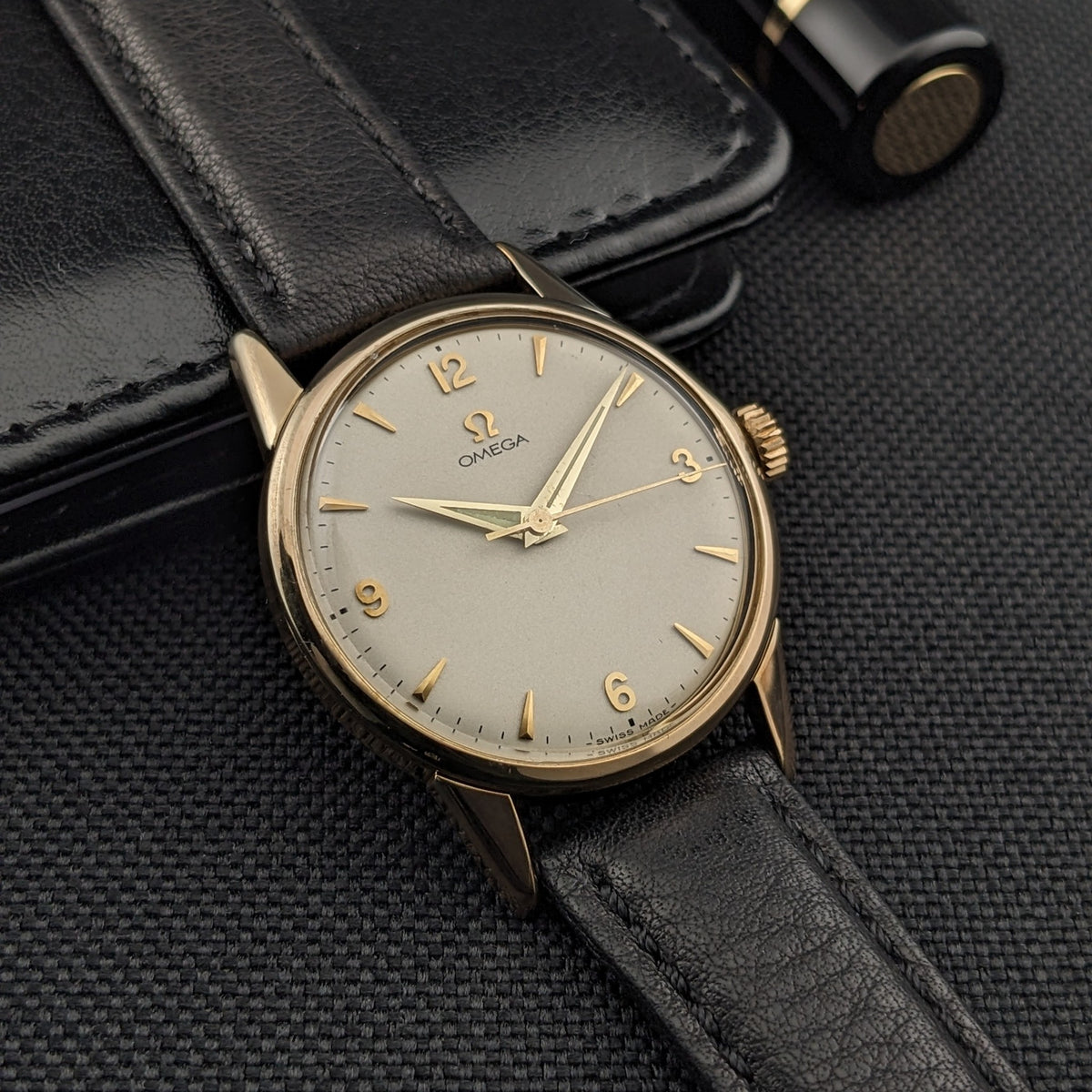 Vue inclinée de l'Omega Classic référence 14392-61-SC montrant son cadran crème, ses aiguilles dorées, ses chiffres et son bracelet en cuir noir.