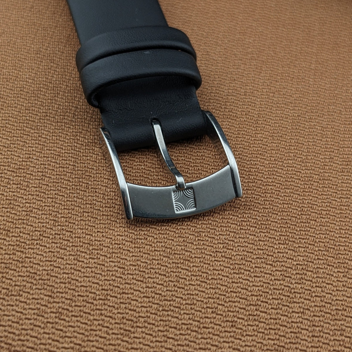 Close-up of the black strap and metal buckle from the Zenith Automatic reference GR 720001 on brown fabric.