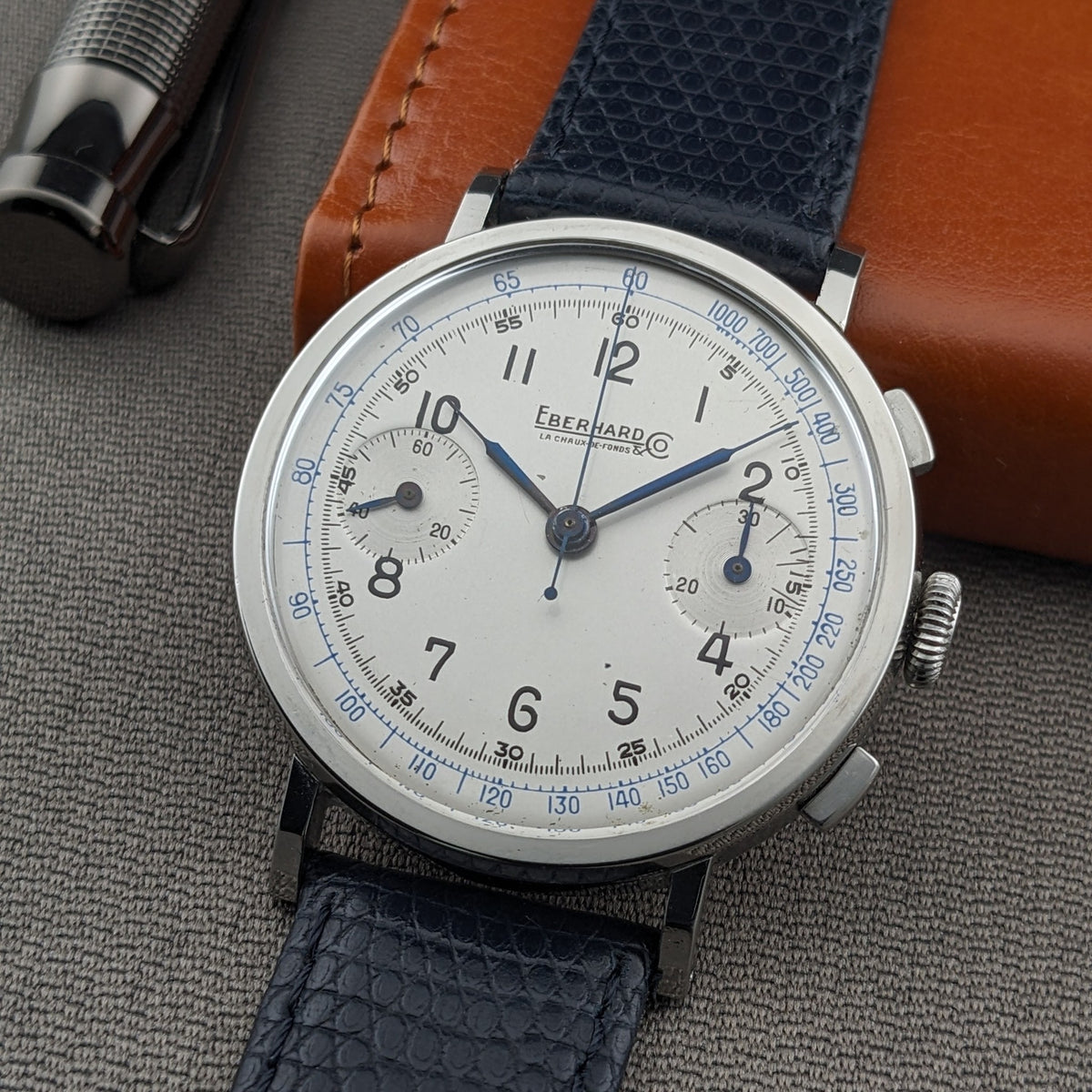 Eberhard & Co.. Pre-Extra Fort front view with cream dial, black numerals, blue scales, two subdials and blue textured strap.