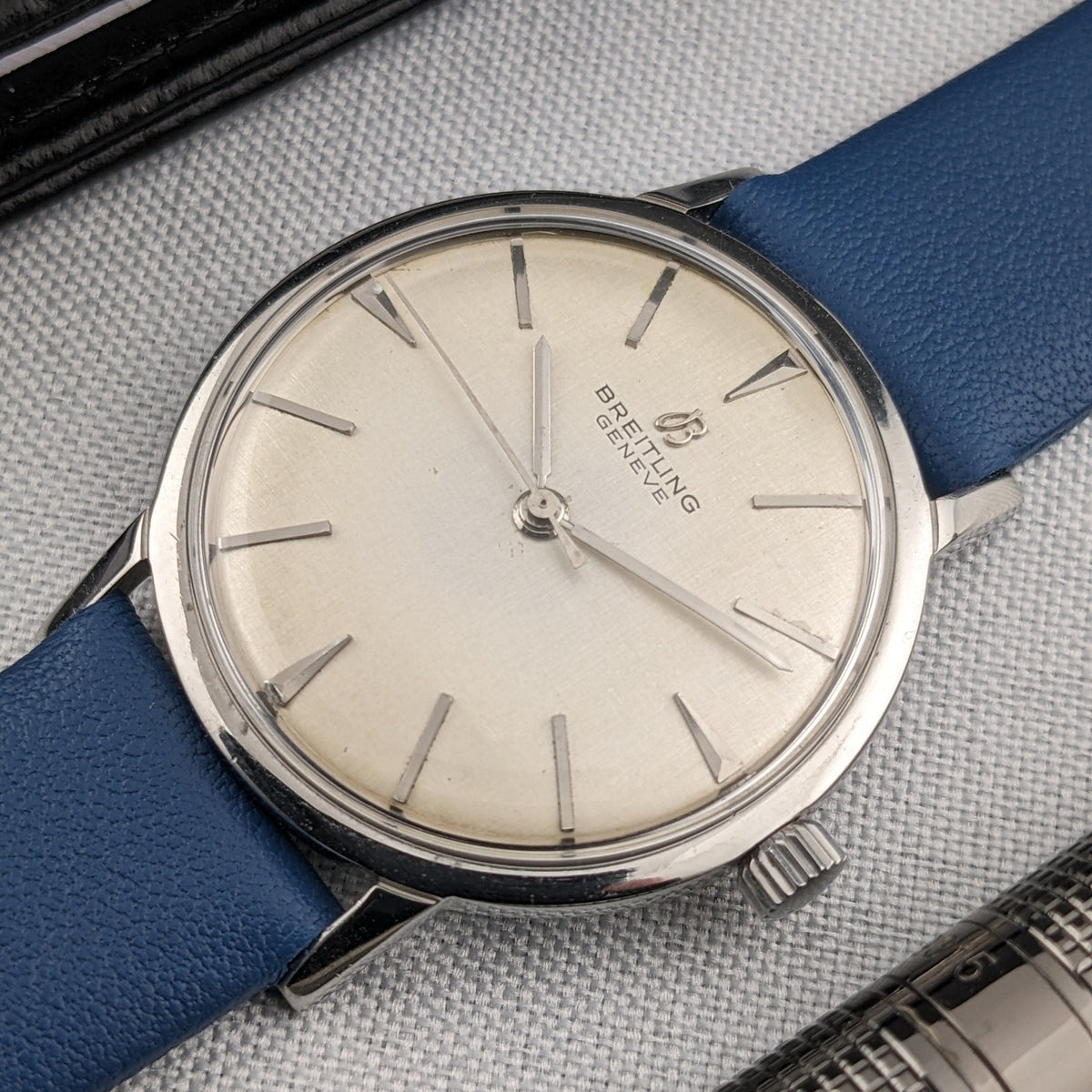 Close view of the Breitling Automatic dial with silver baton markers, central hands, crown and blue leather strap.