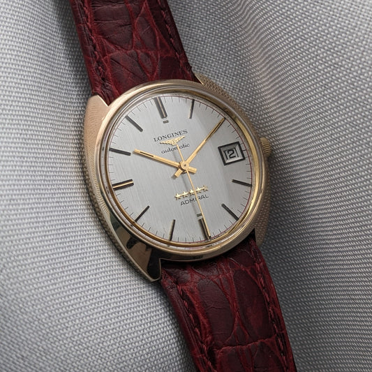 Close view of the Longines Admiral 8343-1 silver dial with gold-tone hands, applied hour markers, date window, and burgundy strap.