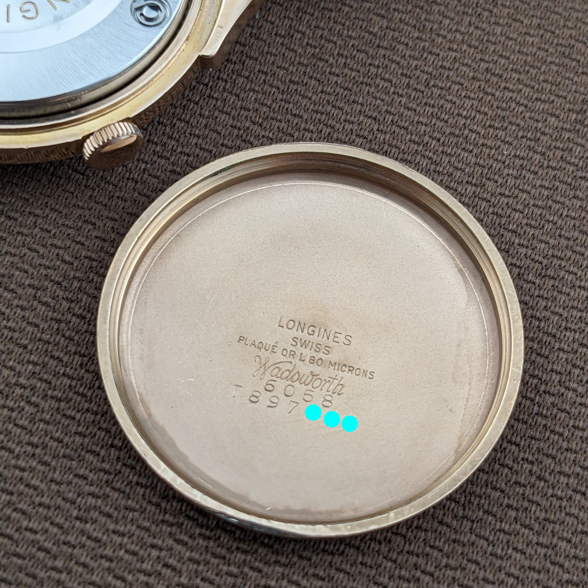 Abgenommener Gehäuseboden der Longines Automatik Referenz 6058 auf braunem Stoff, mit Longines und Gravur innen sichtbar.