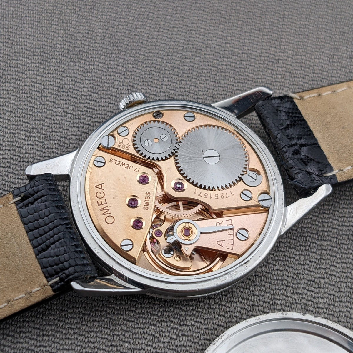 Omega Classic referenza 14391-1 mostrato da dietro con il movimento meccanico esposto, piastre incise, ingranaggi e cinturino nero.