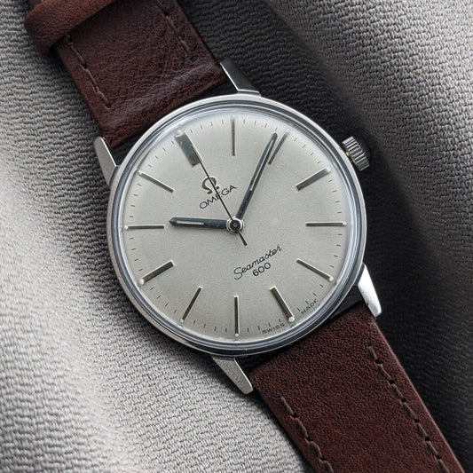 Close angled view of the Omega Seamaster 600 reference 135.011 dial, silver markers, central hands, and brown leather strap.