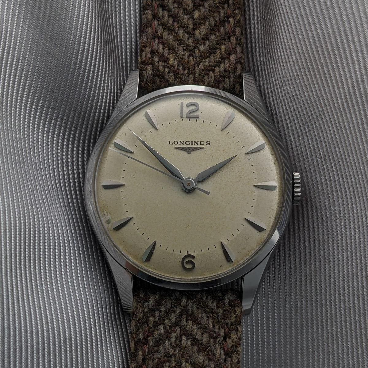 Front view of the Longines Classic reference 8135-5 with a cream dial, applied hour markers, Arabic numerals at 12 and 6, and brown woven strap.