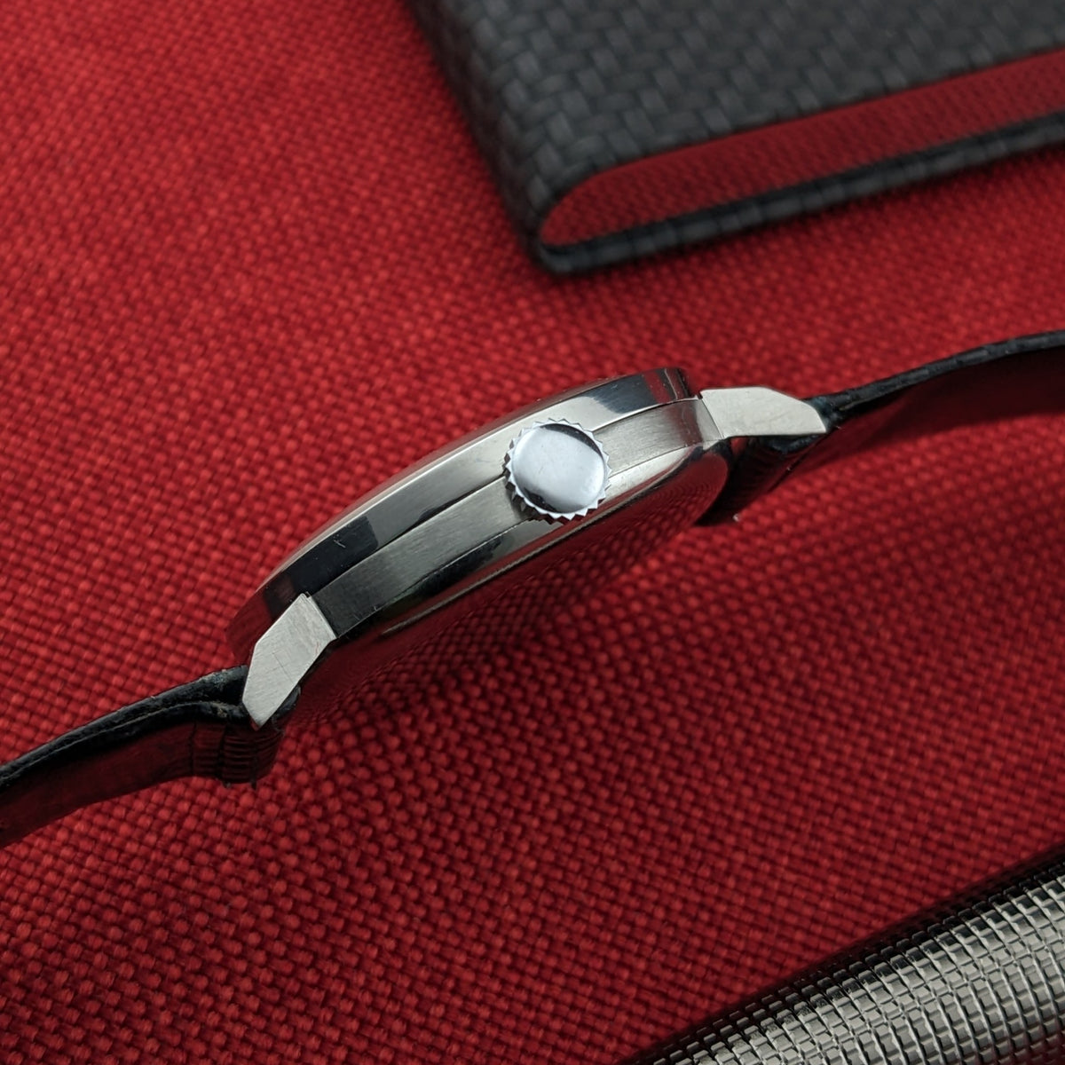 Side profile of the Longines Calatrava reference 20757, showing the round case, crown, lugs, and black strap on red fabric.