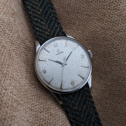 Angled close view of the Omega Classic reference 2810-2 SC dial with numerals, faceted hour markers and green textile strap.