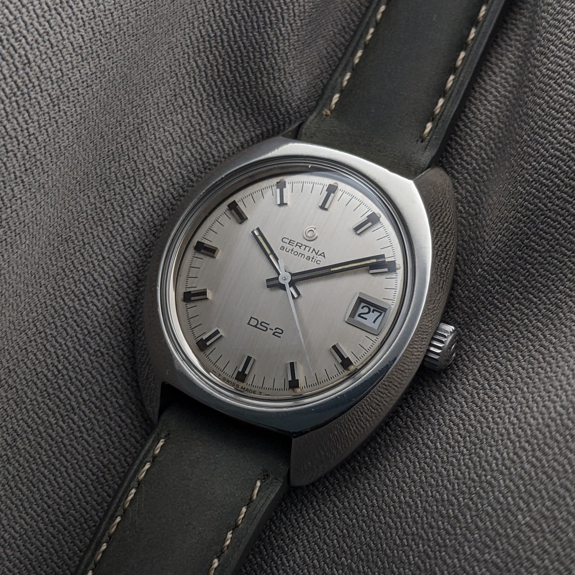 Certina DS-2 Automatic reference 5801 300 resting on textured fabric, with a brushed silver dial, date window, and dark stitched strap.