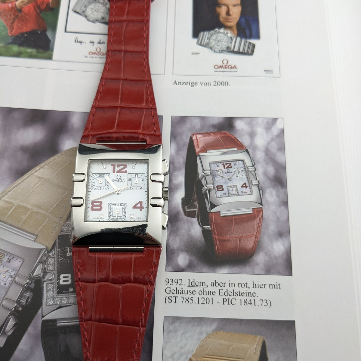 Omega Constellation Quadra 1841.73.31 displayed over an illustrated catalog page featuring red-strap and other Quadra models.