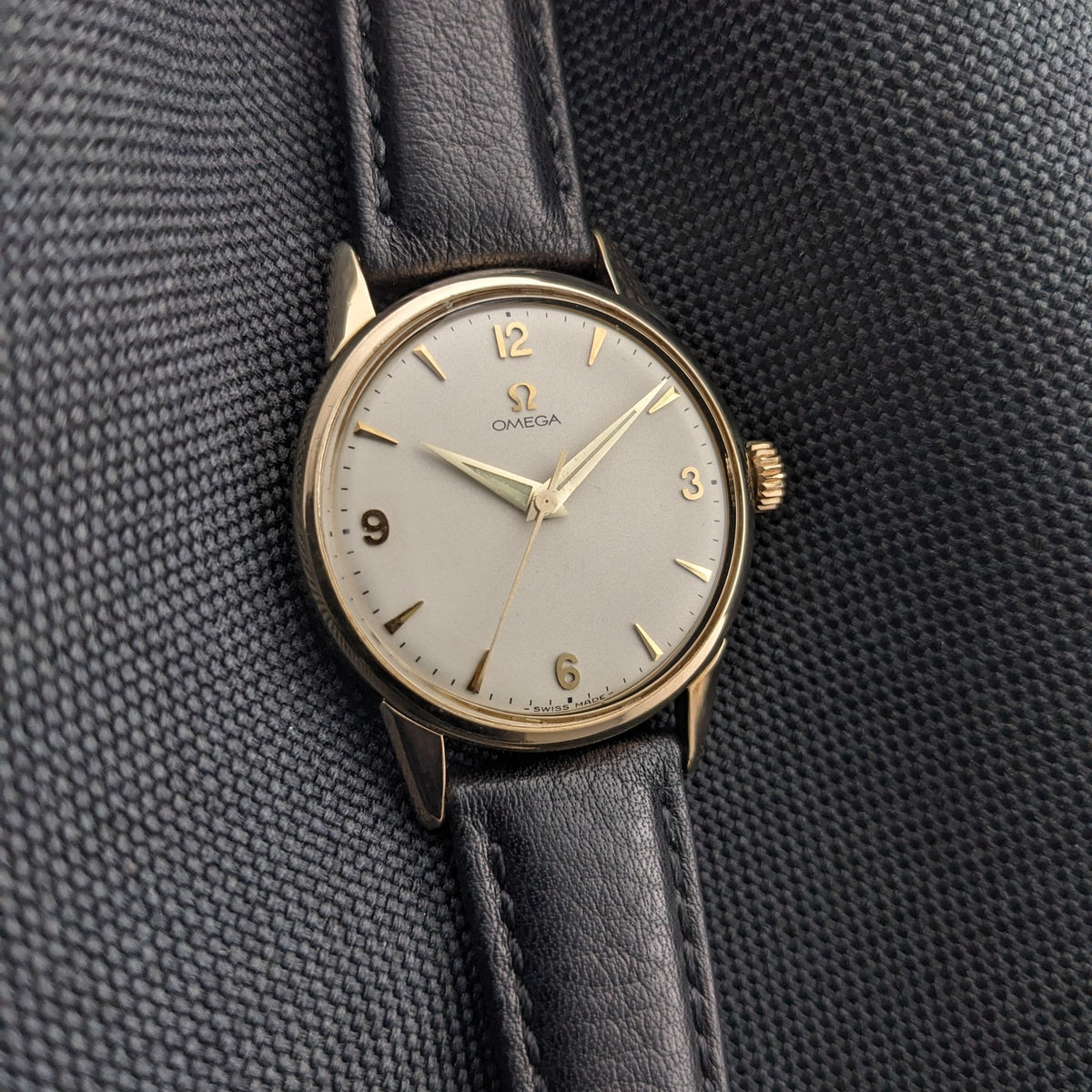 Vue rapprochée de l'Omega Classic référence 14392-61-SC, montrant le cadran crème, les chiffres dorés 12, 3, 6 et 9, et le bracelet noir.