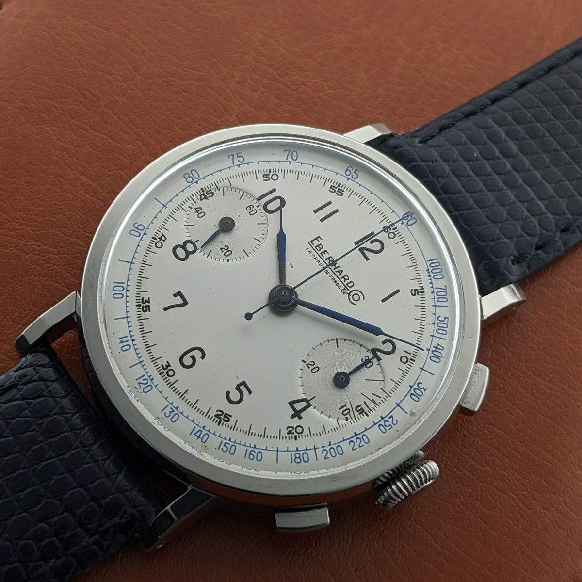 Close view of the Eberhard & Co. Pre-Extra Fort dial on a brown surface, with blue tachymeter scale, black numerals and twin subdials.