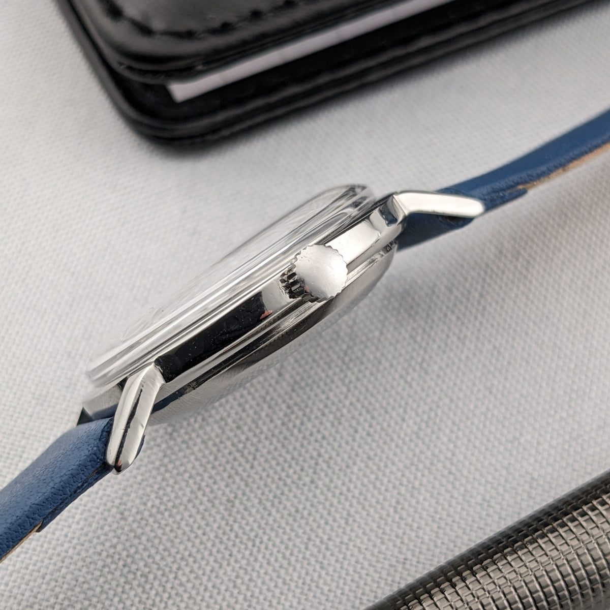 Side profile of the Breitling Automatic watch showing its curved crystal, polished case, crown and blue strap.