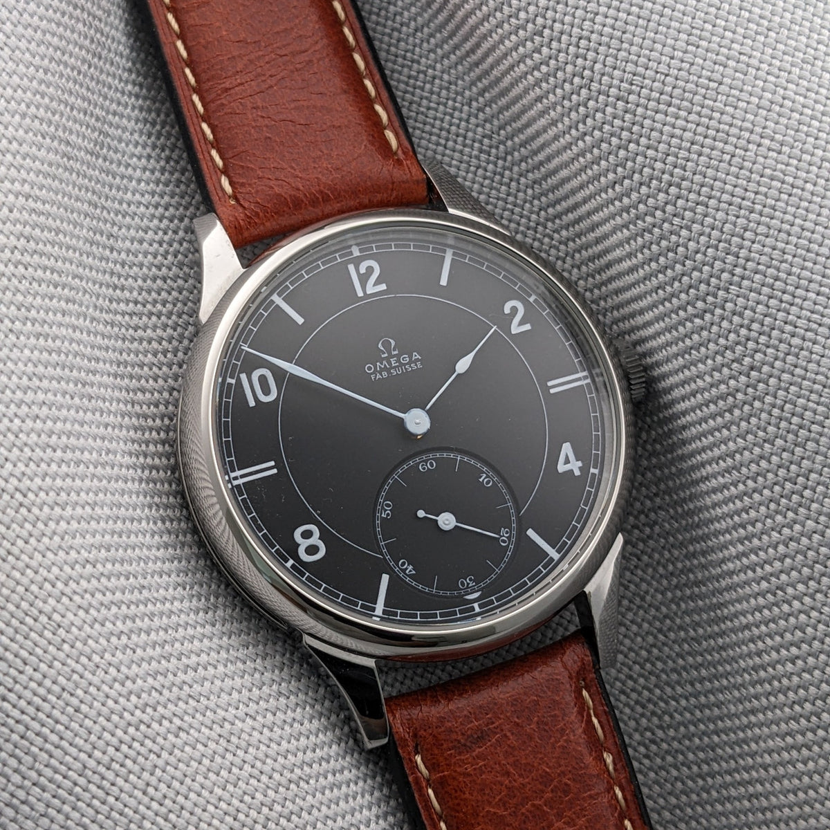Schrägansicht der Omega-Armbanduhr mit dunklem Zifferblatt, kleiner Sekunde, polierter Lünette, Krone und braunem Lederarmband.