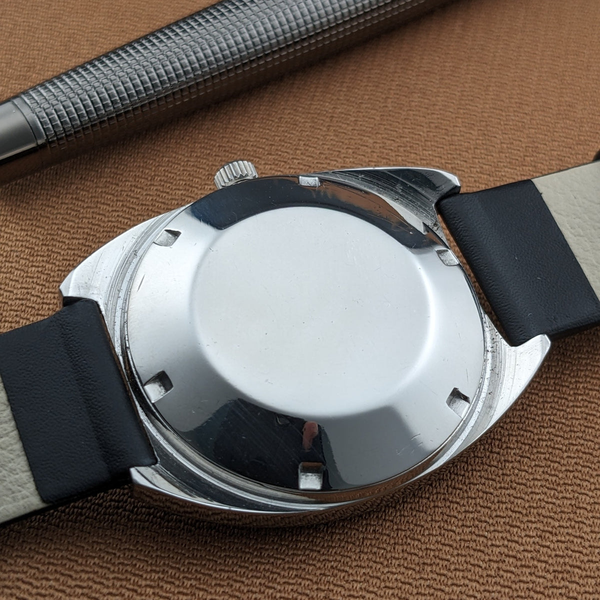 Rear exterior of the Zenith Automatic reference GR 720001 with smooth circular caseback, strap, and silver pen in the background.