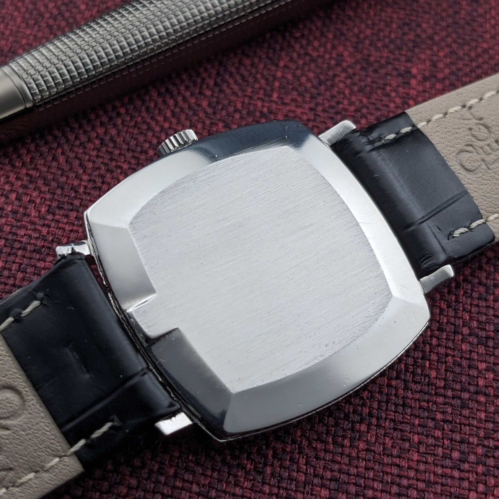 Omega Genève reference 131.022 shown from the back, with its brushed geometric caseback and black leather strap ends visible.