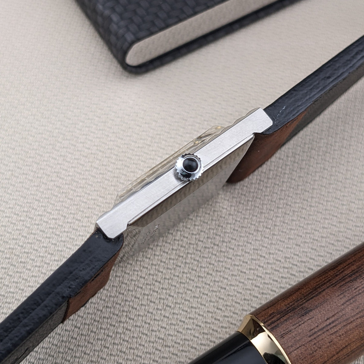 Seitenprofil der Jaeger-LeCoultre Vogue Tank Ref. 9120 zeigt das schlanke Gehäuse, die Krone, dunkle Armbandkanten und einen beigen Stoffhintergrund.