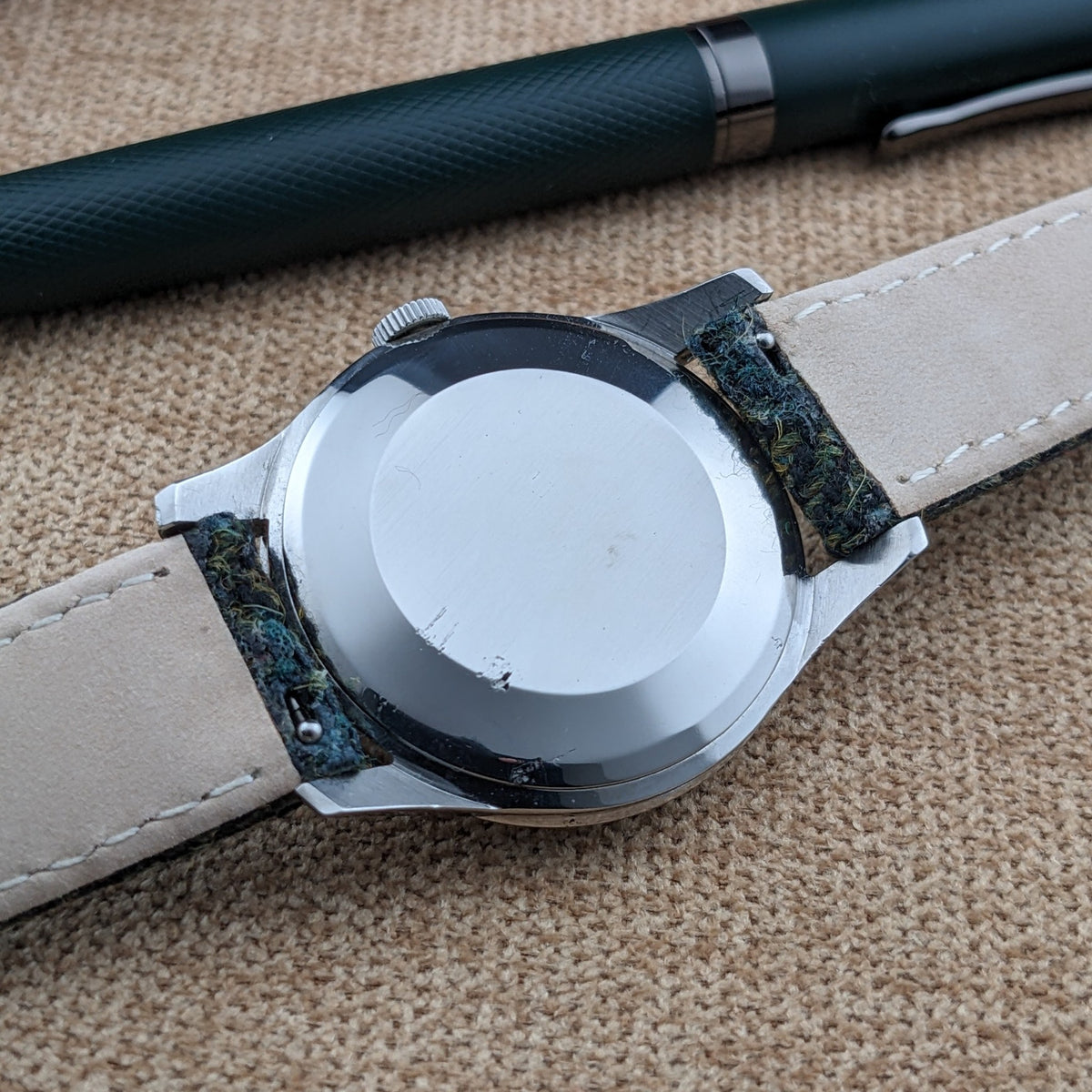 Rückansicht der Omega Classic Referenz 2810-2 SC mit glattem, rundem Gehäuseboden, cremefarbenem Armbandfutter und dunkelgrünen Armbandenden sichtbar.