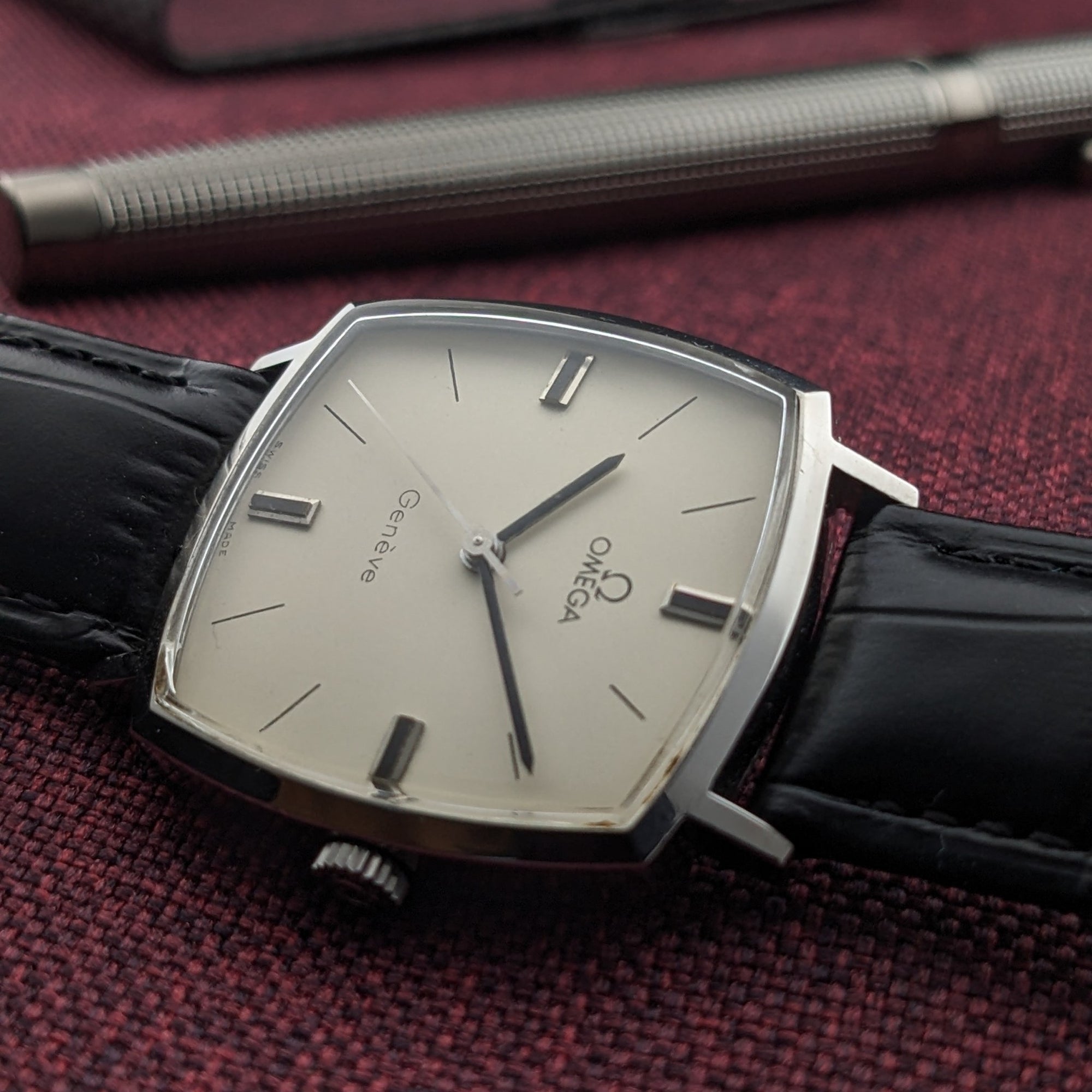 Close-up of the Omega Genève reference 131.022 cream dial, slim minute markers, applied hour bars, and black leather strap.