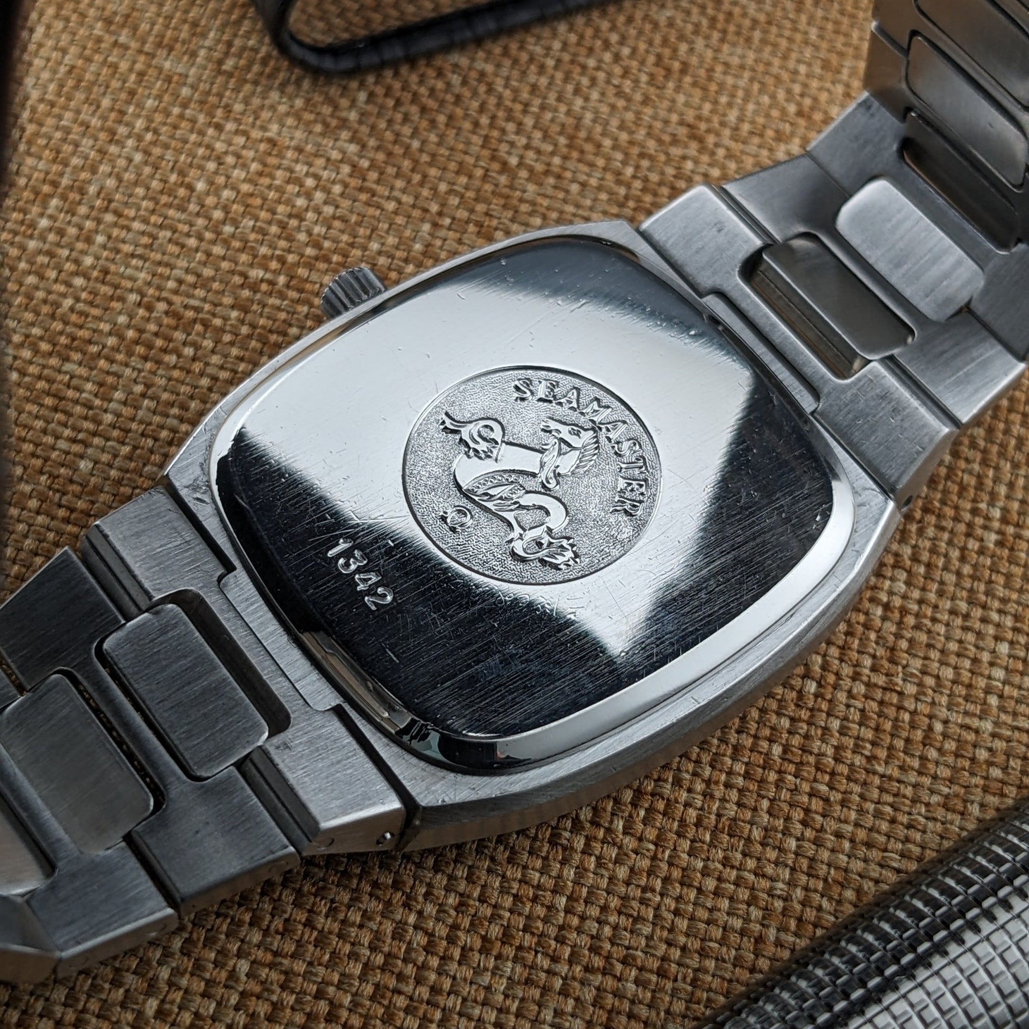 Omega Seamaster reference 196.0166 caseback with central embossed emblem, surrounding text, and bracelet links extending on both sides.