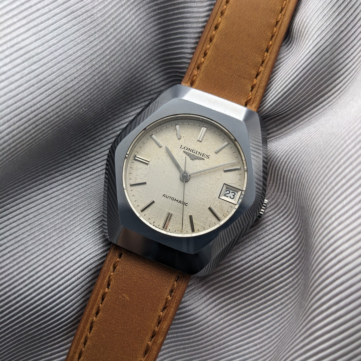 Detailed angled view of the LONGINES Automatic reference 3042-633 with cream dial, faceted case, brown strap and date showing 23.