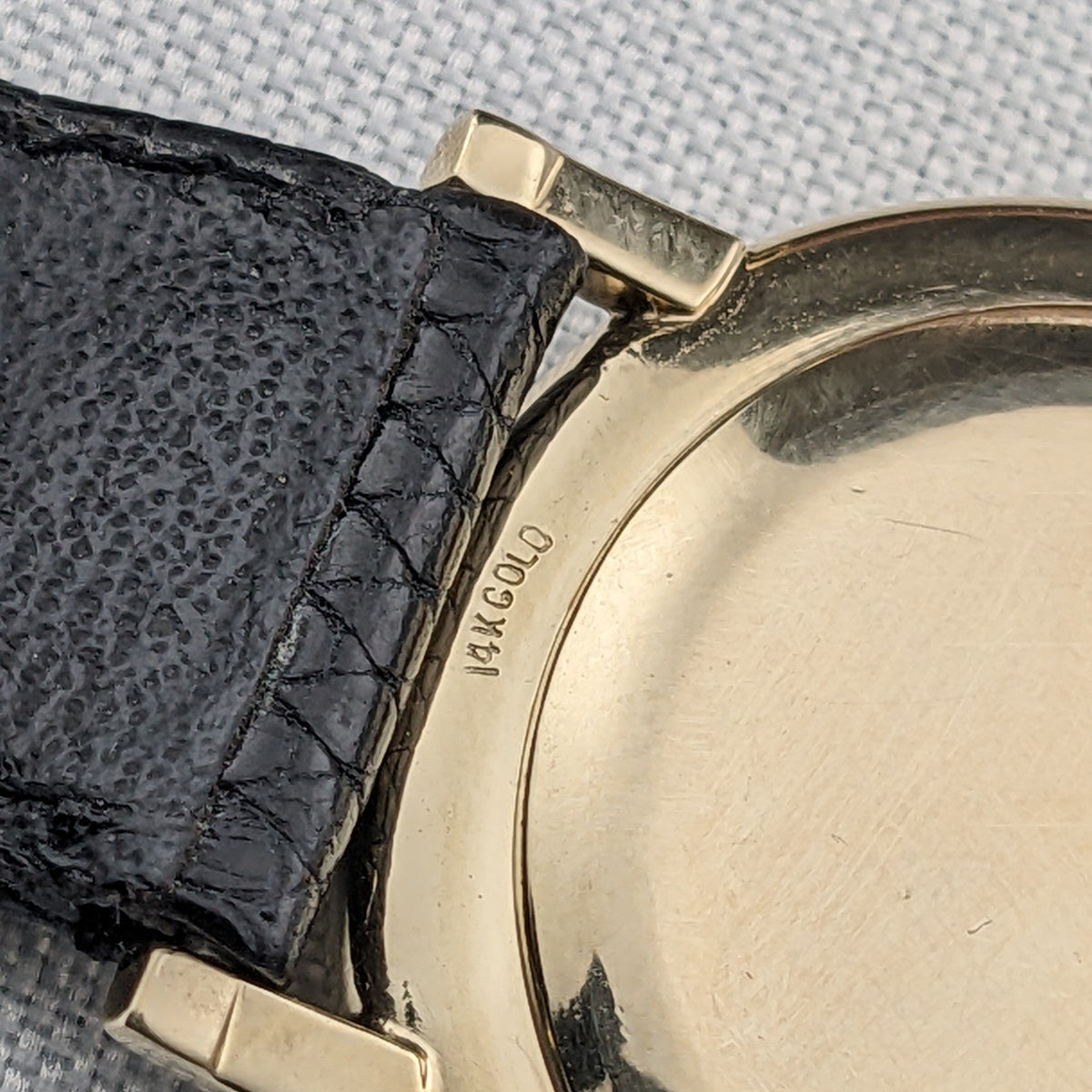 Macro view of the Longines Ultra-Chron 69-556AC caseback edge showing the visible 14K GOLD engraving beside the black strap.
