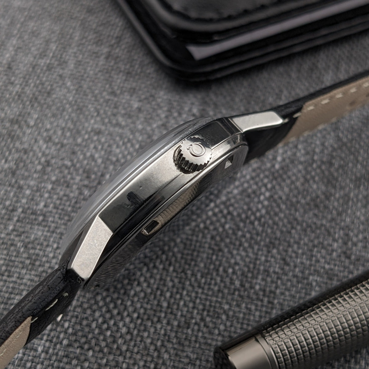 Side profile of the Omega Geneve Automatic reference 166.0163, showing the winding crown, lugs, case edge and black leather strap.