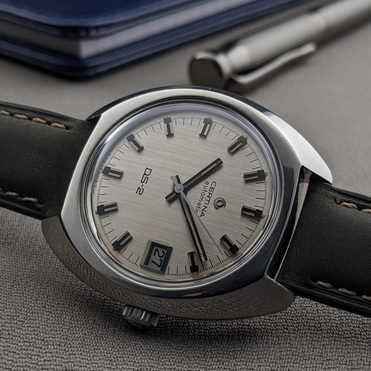 Close angled view of the Certina DS-2 Automatic reference 5801 300 dial, with silver texture, applied markers, date window, and crown visible.