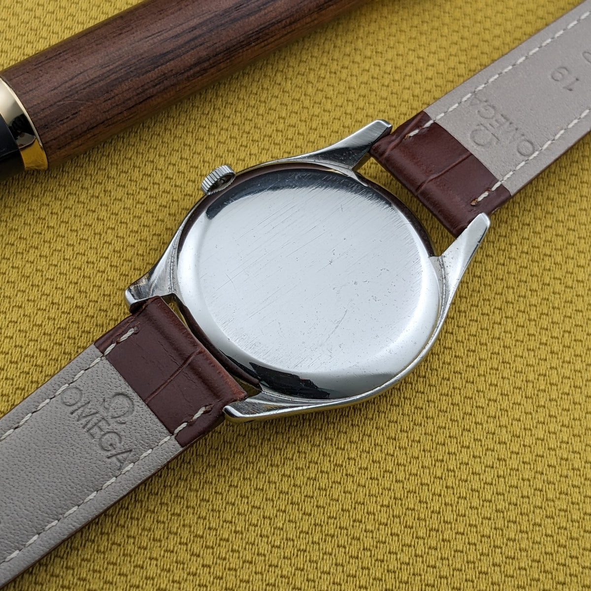 Rückansicht der Omega Jumbo Referenz 2505-10 mit glattem rundem Gehäuseboden, braunem Lederarmband und geprägtem Futter.