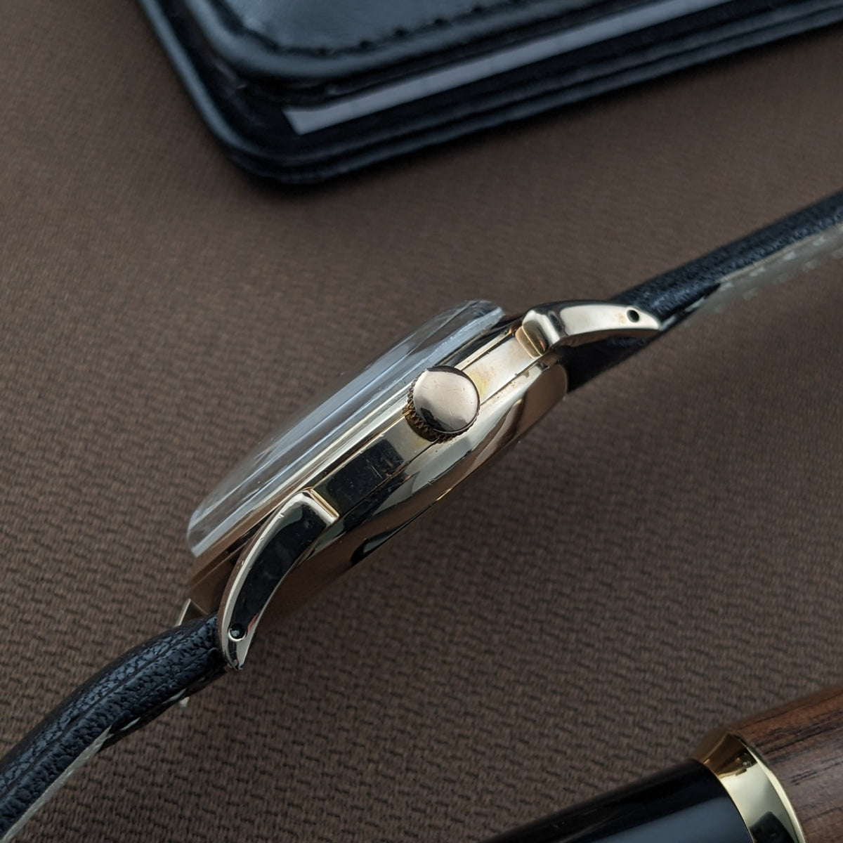Seitenprofil der Longines Automatik Referenz 6058, hebt das runde Gehäuse, die Krone, die Bandanstöße und das schwarze Lederarmband hervor.