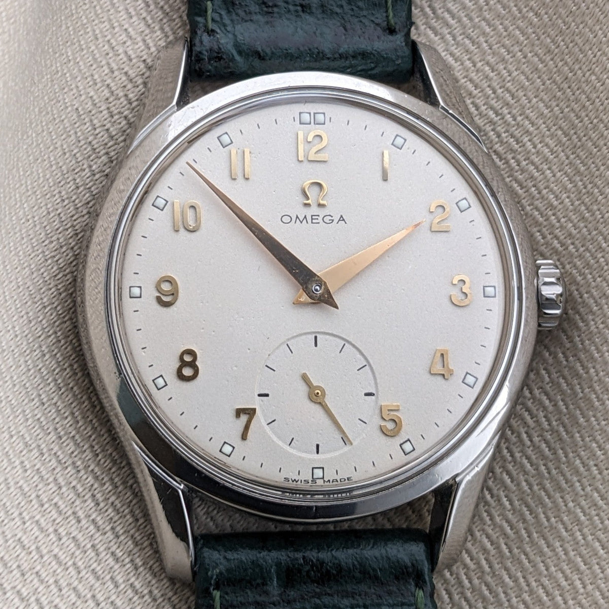 Primo piano verticale dell'OMEGA Classic referenza 2639-11 con quadrante argentato, lancette e numeri dorati, corona e cinturino verde.