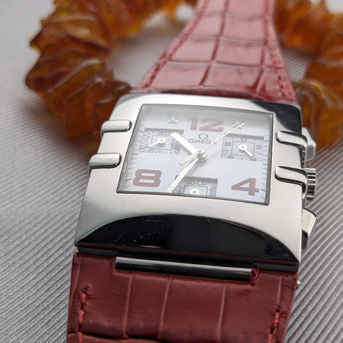 Low-angle front view of the Omega Constellation Quadra 1841.73.31 highlighting the white dial, red numerals, case, and red strap.