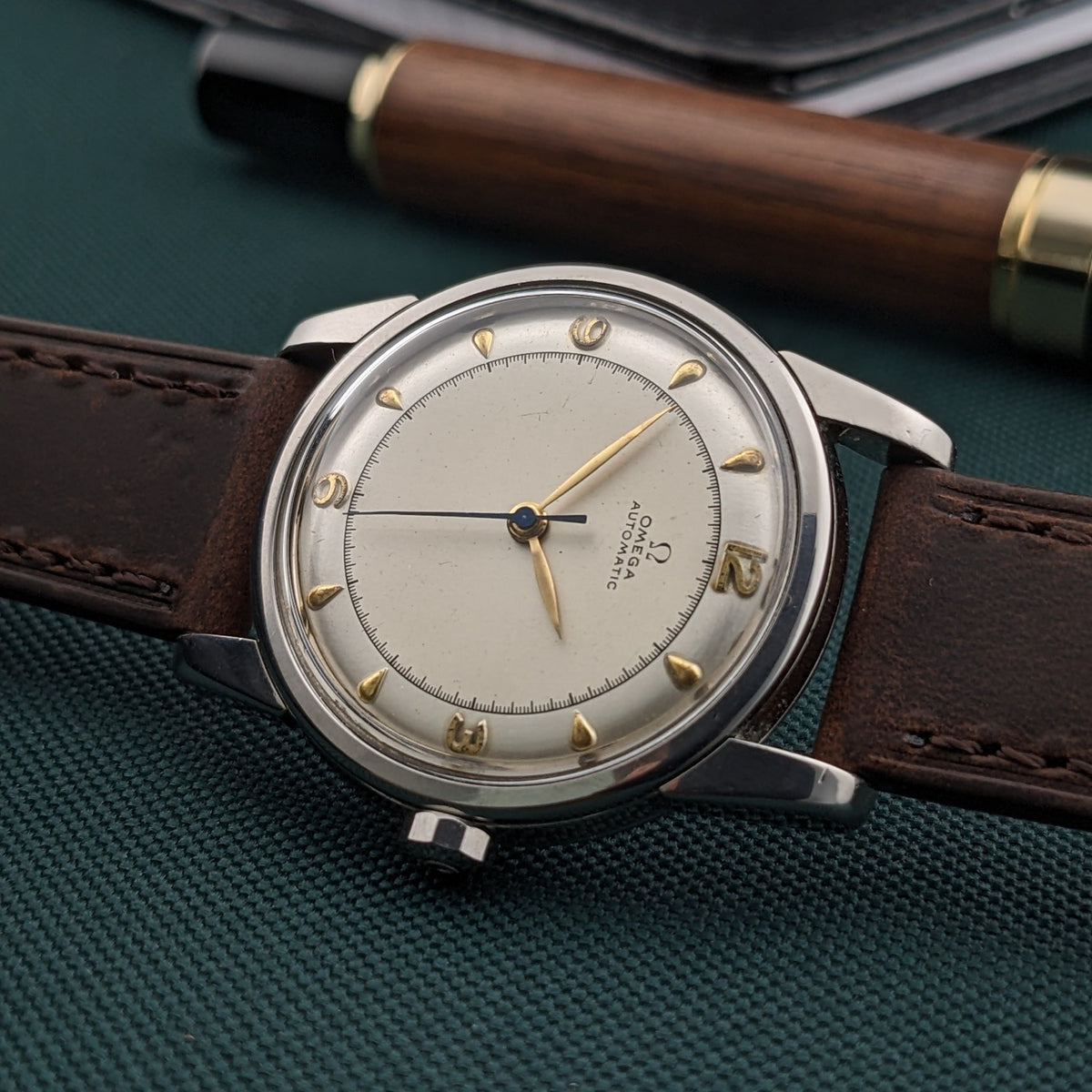 Angled close view of the Omega Automatic Bumper reference 2767-4 SC showing its cream dial, gold-tone numerals and brown leather strap.
