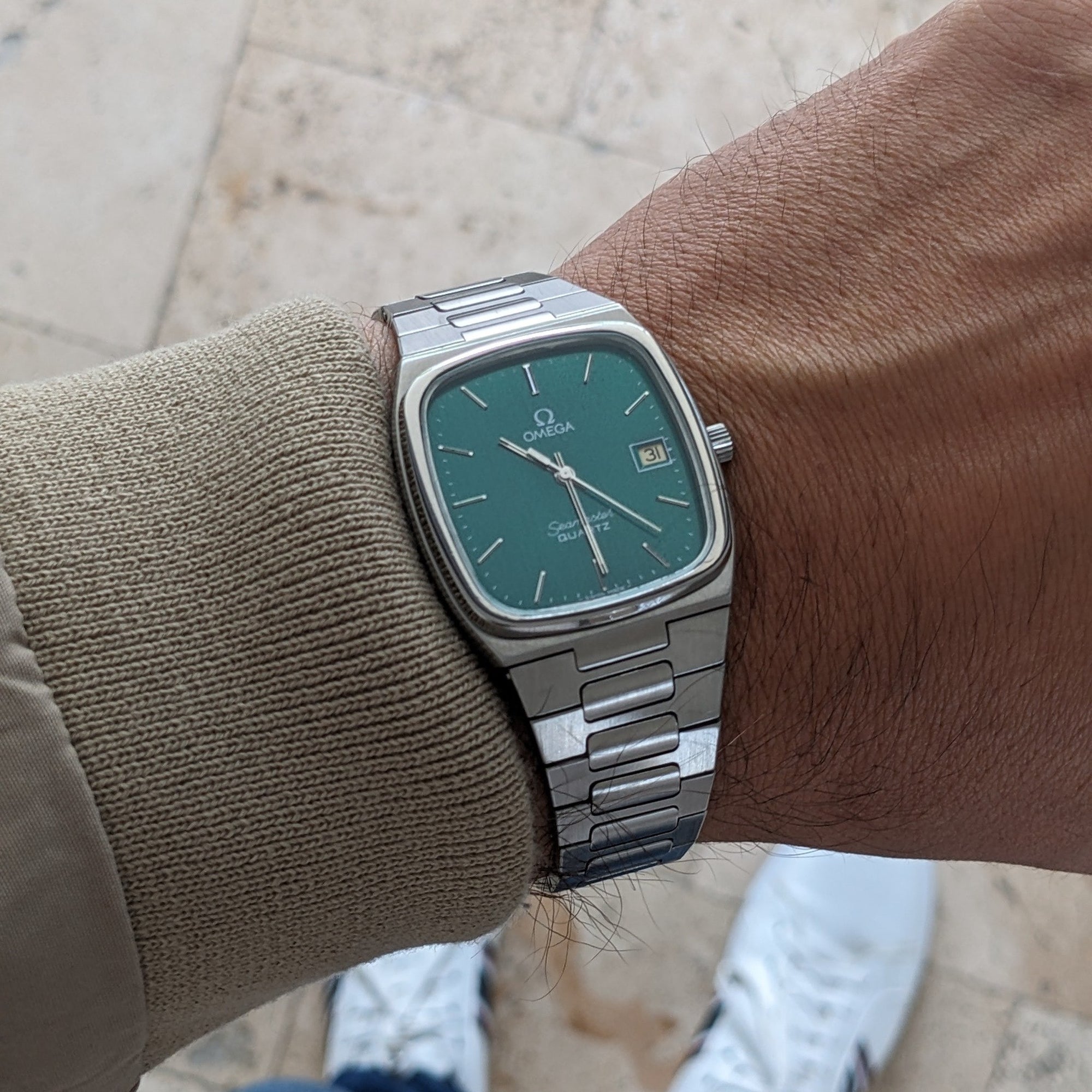 Omega Seamaster reference 196.0166 worn on a wrist, showing the teal dial, date window, silver case, and integrated bracelet.